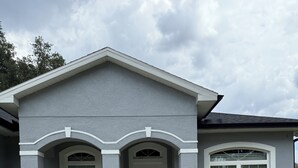 Une maison à deux étages avec un porche à l’avant, un garage et une pelouse bien entretenue.