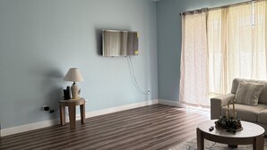 A living room with a ceiling fan, a mounted TV, a sofa, a coffee table, and a lamp.
