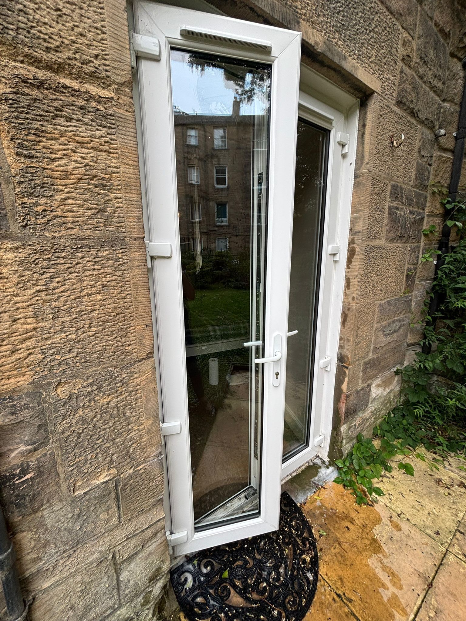 A white door with a glass panel, set in a stone wall with a small step leading up to it.