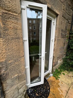 A white door with a glass panel, set in a stone wall with a small step leading up to it. - Perfect 3-bedroom apartment in charming Edinburgh close to city center (Edinburgh)