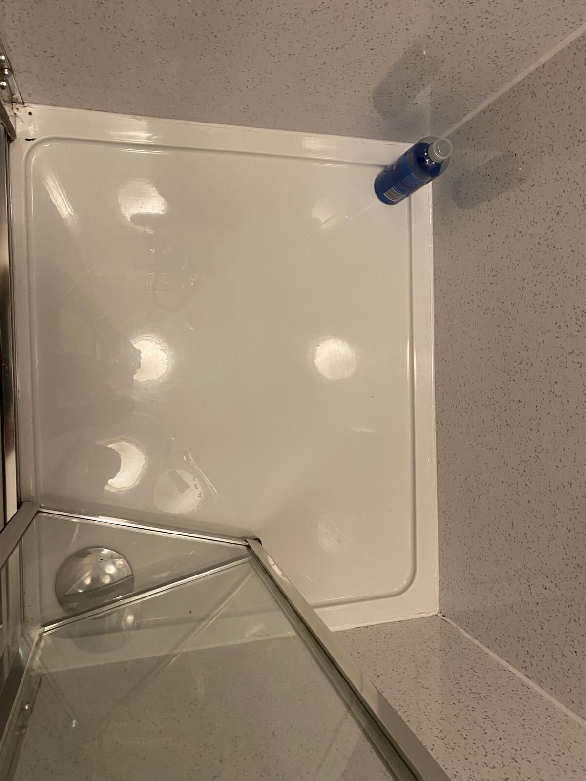 A bathroom with a white bathtub, a glass shower enclosure, and a blue bottle on the wall.