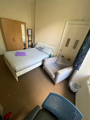 A bedroom with a bed, a chair, a wardrobe, and a radiator. - Perfect 3-bedroom apartment in charming Edinburgh close to city center (Edinburgh)