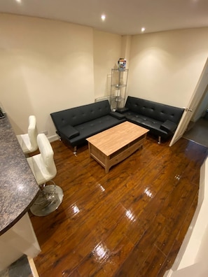 A modern living room with a sectional sofa, a coffee table, and a glass shelving unit. - Perfect 3-bedroom apartment in charming Edinburgh close to city center (Edinburgh)