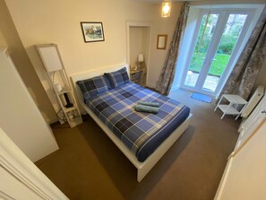 A bedroom with a bed, a bedside table, a lamp, a picture on the wall, and a view of the outdoors through a door. - Perfect 3-bedroom apartment in charming Edinburgh close to city center (Edinburgh)