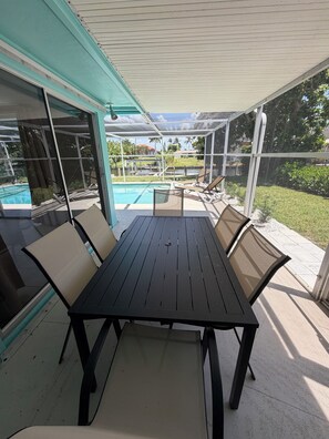 Eine Terrasse im Freien mit Tisch und Stühlen, einem Pool und Blick auf die umliegende Landschaft.