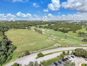 Ein Golfplatz mit Parkplatz und Gebäuden im Hintergrund.