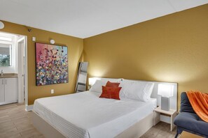 Habitació d'hotel amb un llit gran, una nitòria amb una làmpada, un quadre a la paret i vista al bany.
