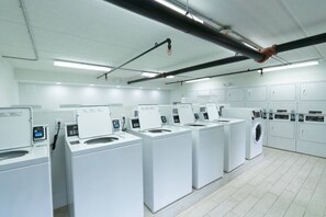 Een wasserette met meerdere wasmachines en drogers, opgesteld in rijen.