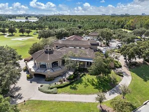 A large, multi-story residential building with a tiled roof, surrounded by well-maintained lawns and trees. - Bright Disney Suite + Pool & Parking | Orl (Kissimmee)