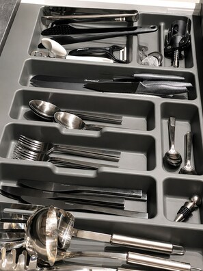 A drawer with compartments containing various kitchen utensils such as spoons, forks, and knives.