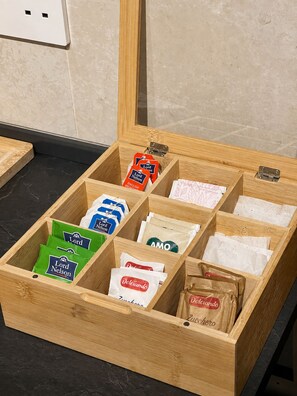 A wooden storage box with compartments containing various food items. - Modern & Stylish 3BR Apartment in Central Malta (L-Imsida)