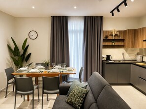 A modern living space with a dining area, a sofa, and a kitchen. - Modern & Stylish 3BR Apartment in Central Malta (L-Imsida)
