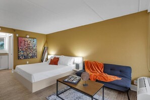 Une chambre d’hôtel avec un lit, un canapé, une petite table et un tableau au mur.