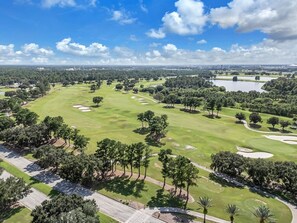 A golf course with sand bunkers, trees, and a clear sky. - Stylish Disney Stay + Free Parking | Orl (Kissimmee)