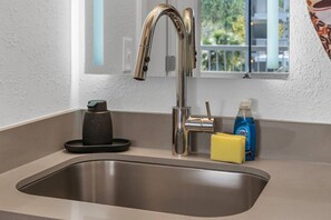 Ein Edelstahl-Spülbecken mit modernem Wasserhahn, einer Kaffeemaschine und einer Flasche Dawn Spülmittel.