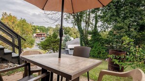 Una terrazza esterna con tavolo e sedie, una scala in legno e vista su una zona residenziale.