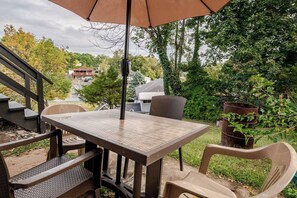 Une terrasse extérieure avec une table et des chaises, un escalier en bois et une vue sur un quartier résidentiel.