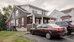 Una casa a due piani con garage, vialetto e un'auto parcheggiata.
