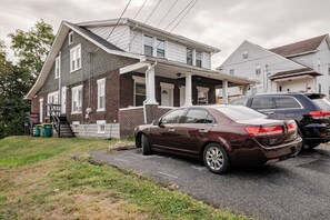 Une maison à deux étages avec un garage, une allée et une voiture garée.