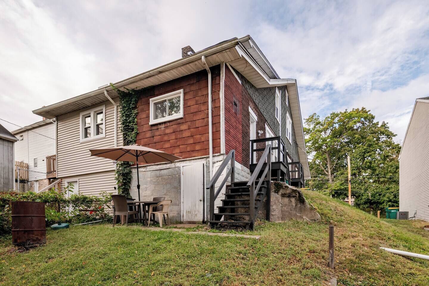 A two-story house with a covered patio area, a staircase leading to the upper floor, and a small front yard.