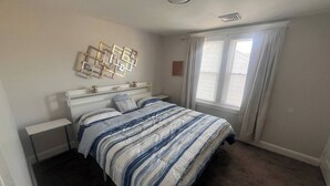 Una camera da letto con un letto, comodini, una finestra con tende e un lampadario a parete.