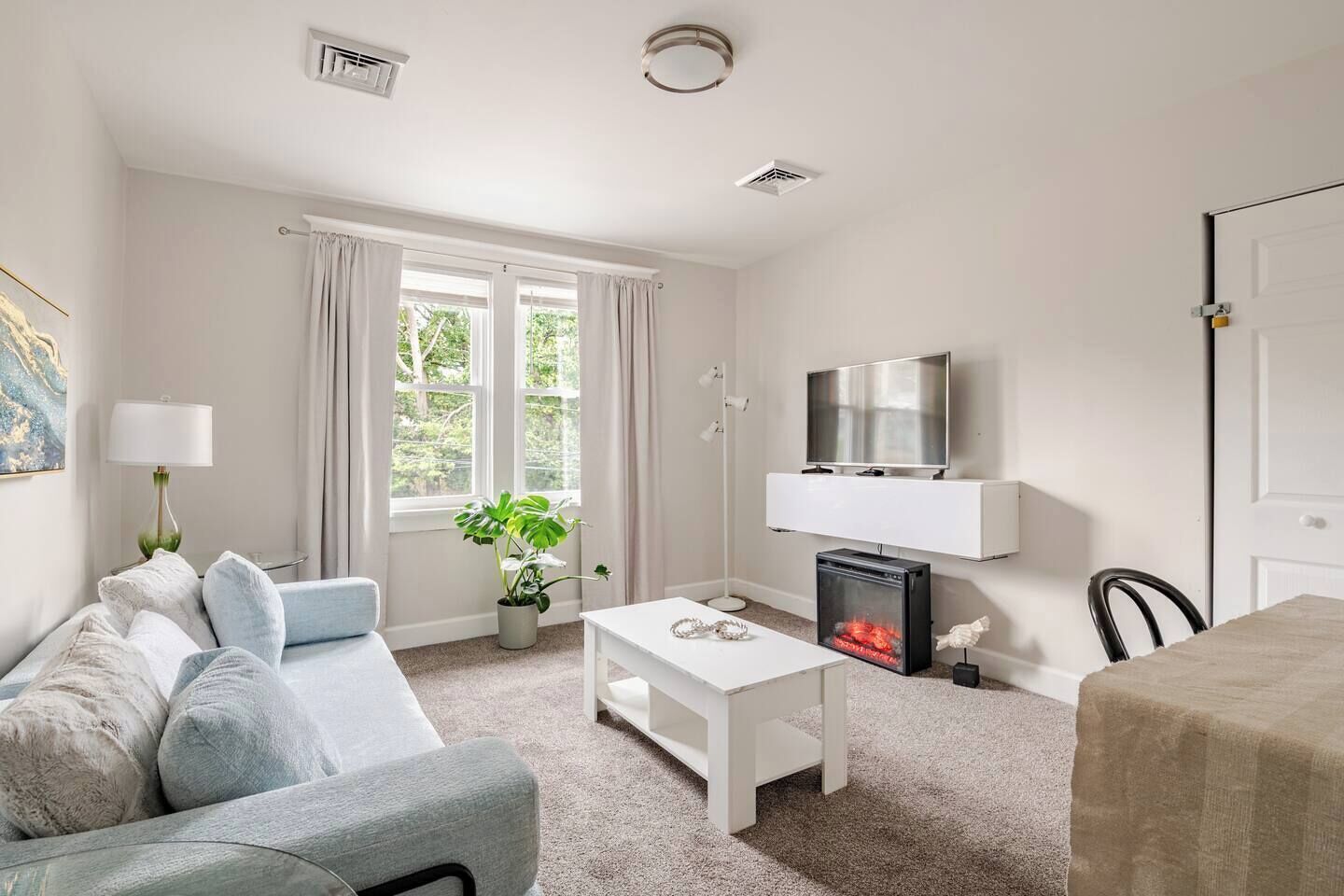 A modern living room with a sofa, a coffee table, a TV, and a fireplace.