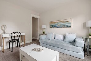 Un salon avec un canapé bleu clair, une table basse blanche, un fauteuil noir et une table en verre avec une lampe.