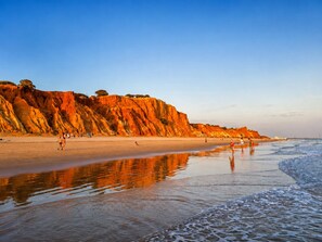 A beach with a rocky cliff and calm waters reflecting the sky. - AE Flat Falésia - 1-Bedroom Apartment in Praia da Falésia with Air Conditioning and Wi-Fi (Albufeira)