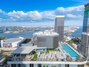 A modern hotel with a rooftop pool, a helipad, and a view of the city skyline and water. - Stunning Skyline & Bay View Luxury Apartment (Miami)