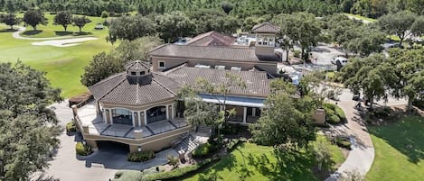 A large, multi-story residential building with a tiled roof, surrounded by well-maintained lawns and trees.