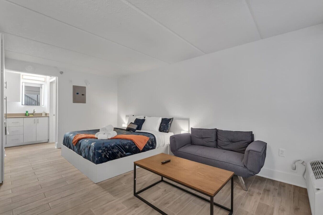 A modern bedroom with a bed, a gray sofa, and a wooden coffee table.