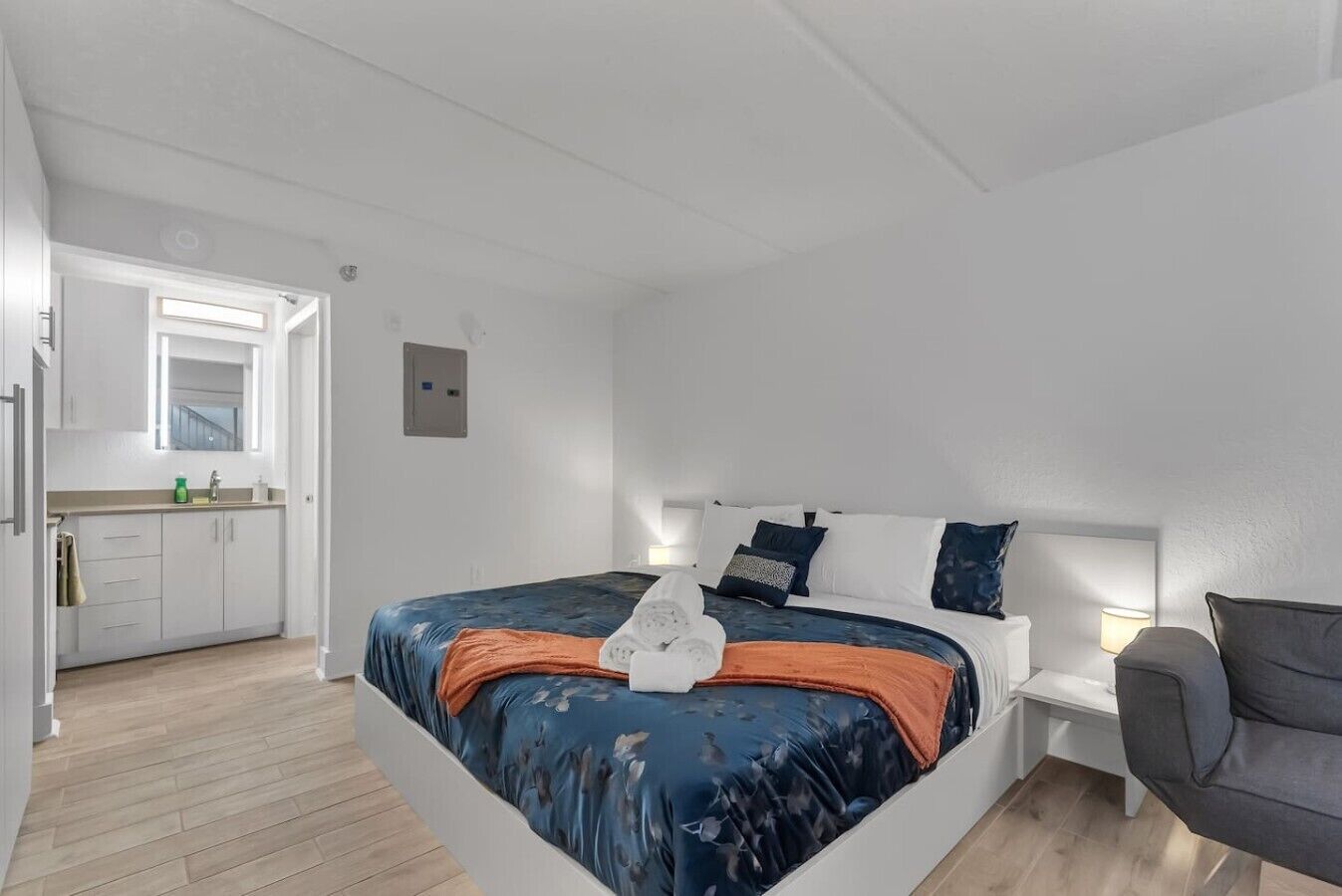 Een slaapkamer met een bed, nachtkastje en een stoel.
