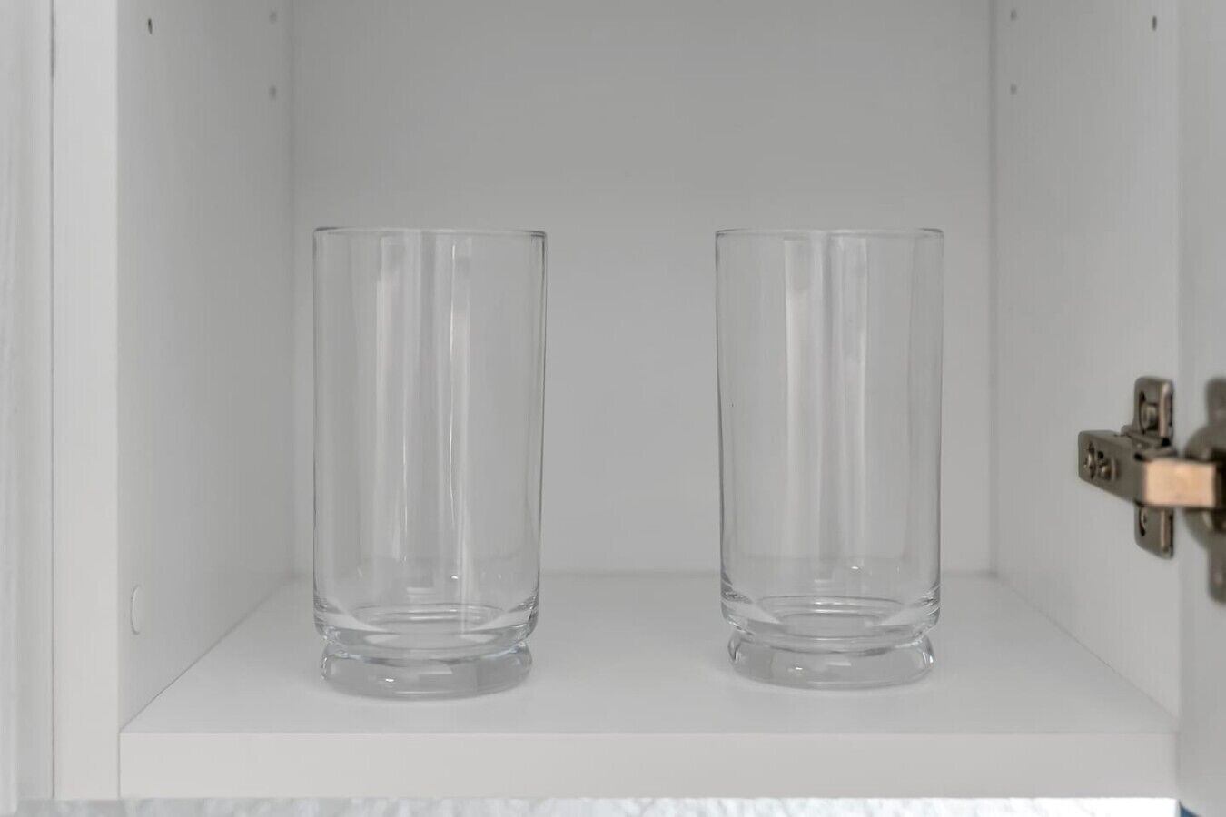 Two clear glass bottles on a white shelf.