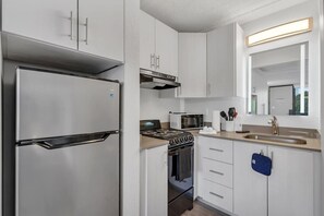 Eine moderne Küche mit Edelstahlgeräten, einer Mikrowelle, einem Gasherd und einem Spülbecken.