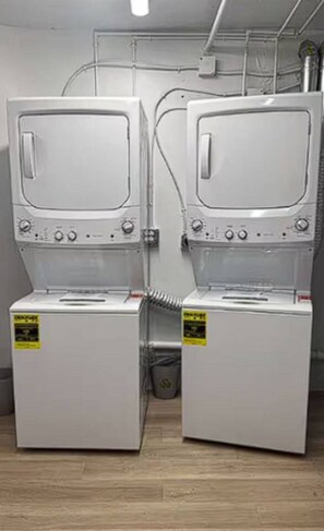 Two stacked washing machines in a room with a wooden floor and visible plumbing. - Cozy Retreat with Stunning Water View | Fort Myers (Fort Myers)