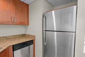 A kitchen with wooden cabinets, a stainless steel refrigerator, and a dishwasher. - Cozy Retreat with Stunning Water View | Fort Myers (Fort Myers)