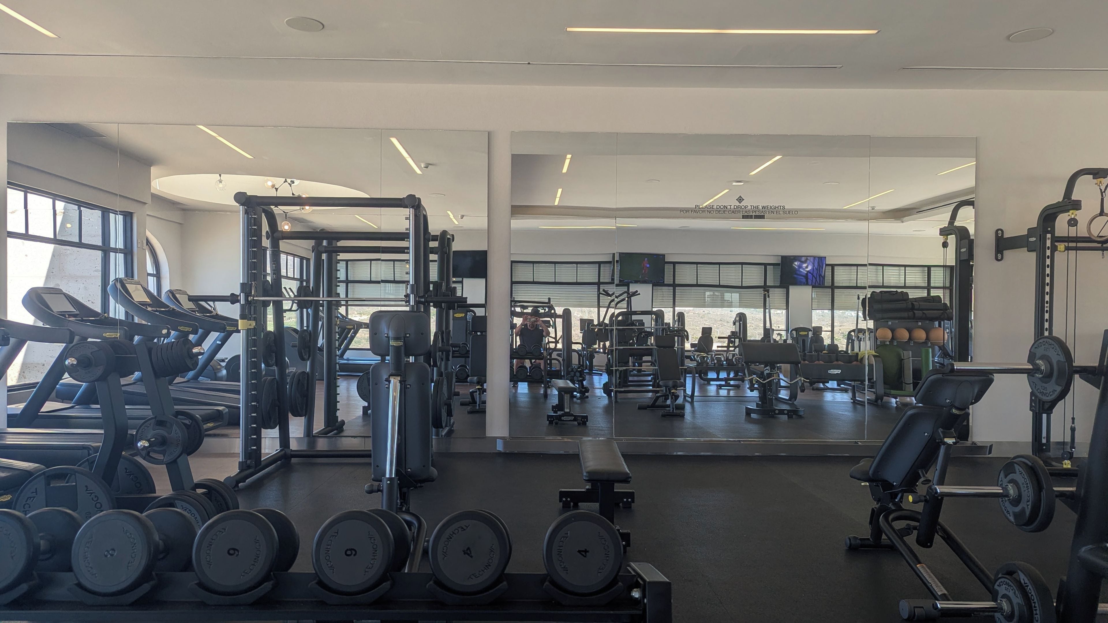 A gym with various exercise equipment, including treadmills, weight machines, and free weights.