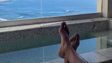 A person relaxing by a pool with a view of the ocean.