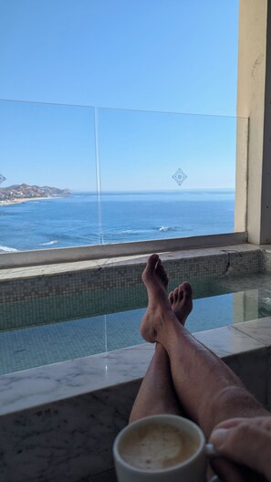 Una persona relaxant-se a la piscina amb vista a l'oceà.