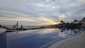 Una piscina con vista sull'oceano e un tramonto.