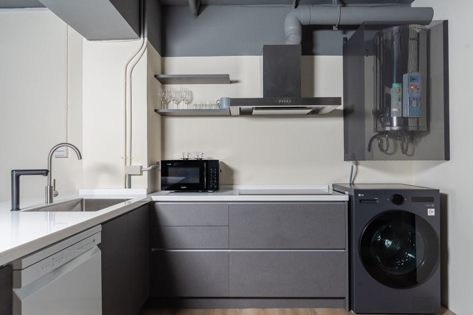 A compact kitchen with a built-in microwave, a washing machine, and a modern faucet.