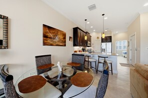 A modern kitchen with dark cabinets, a central island, and a dining area with wicker chairs. - Gulf Breeze Getaway 4BR St Pete Family Retreat (St. Petersburg)
