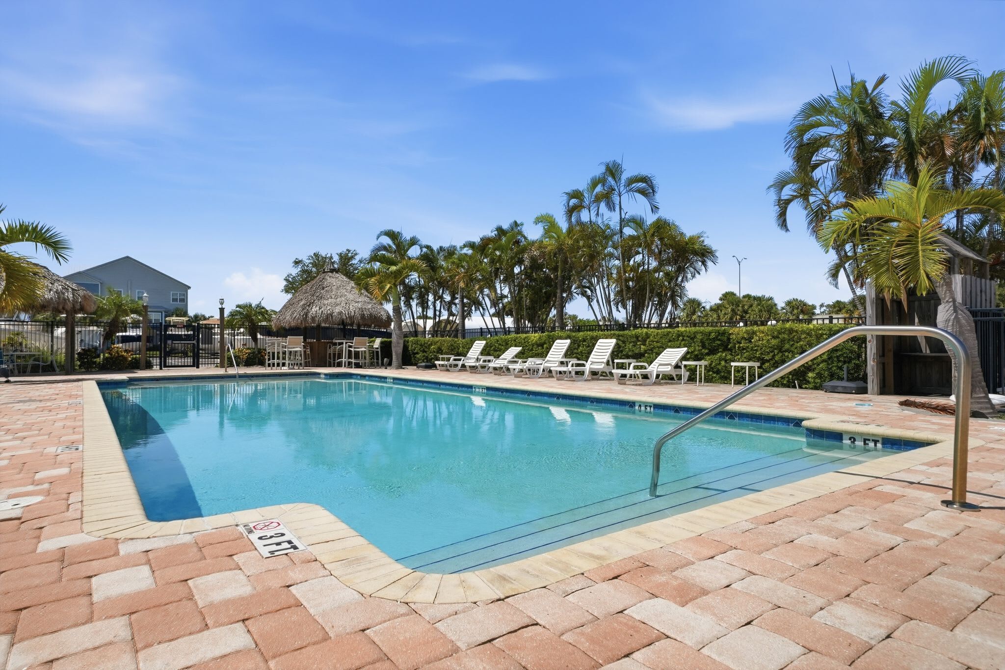 A swimming pool with lounge chairs and palm trees.