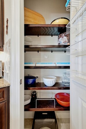 A kitchen with wooden shelves, a coffee maker, a kettle, and a trash bin. - Gulf Breeze Getaway 4BR St Pete Family Retreat (St. Petersburg)