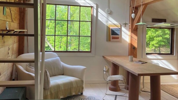 Una habitación con un ventanal grande, un sofá, una mesa de comedor y una estructura de techo de madera.