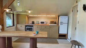 Una cocina compacta con una mesa de madera, un refrigerador, un microondas y una cafetera.