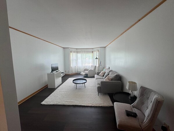 A modern living room with a sofa set, a coffee table, a TV, and a lamp.