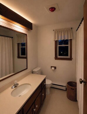 Een badkamer met een wastafel, spiegel, toilet en raam.