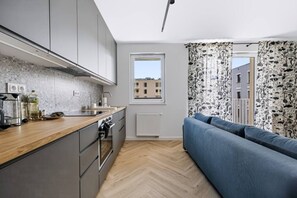Eine moderne Küche mit grauen Schränken, einer Holz Arbeitsplatte und einem eingebauten Backofen.