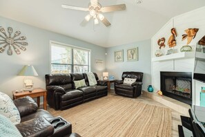 Ein Wohnzimmer mit Kamin, Deckenventilator und Wanduhr.
